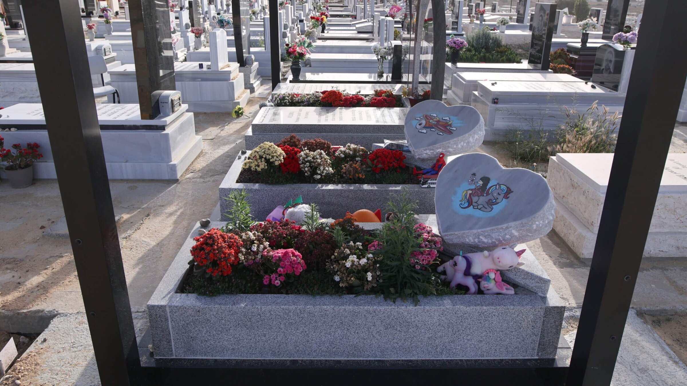 The graves of 8-year-old Aline Kapshitter and her 5-year-old brother, Eitan, outside the perimeter fence of the cemetery in Dimona.
