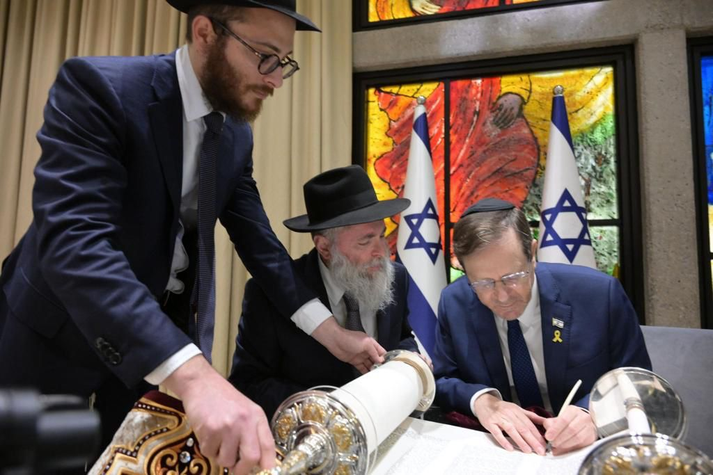 Israeli President Isaac Herzog writes the final letter to in a Torah initiated by Ukraine’s president Volodymyr Zelensky, April 2024 in Jerusalem. (Courtesy Israeli president’s office)