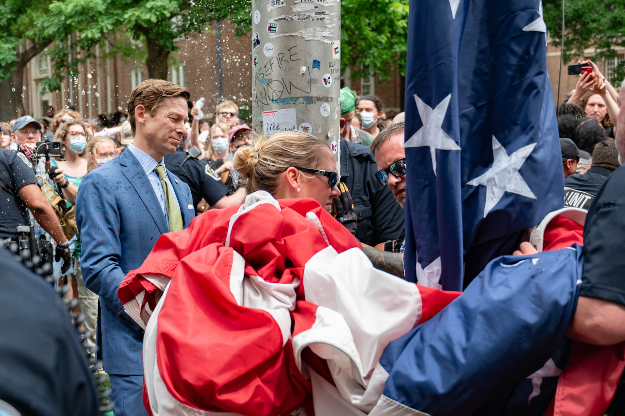 Police escort Lee Roberts, interim chancellor of the University of North Carolina, through a crowd of protesters to restore an American flag to a pole at the center of campus.