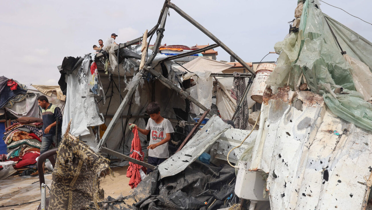 A Palestinian boy searches the debris of a camp for internally displaced people in Rafah after a strike by Israel. 