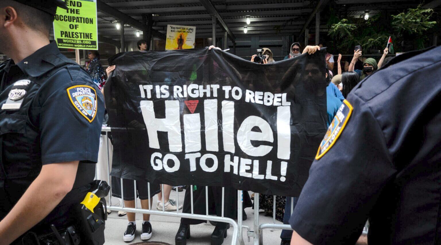Protesters demonstrating against Hillel at Baruch College hold a sign featuring an inverted red triangle, a symbol that Hamas uses to show military targets in videos posted to social media.