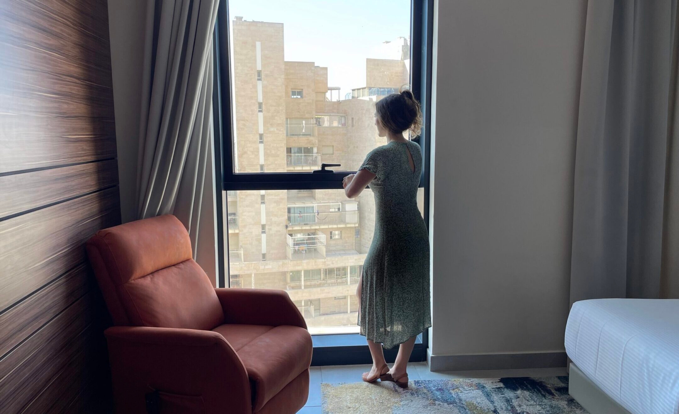 A woman looks out the window at the Yirmiyahu33 complex, home to Israel’s first hotel for women and couples who have experienced stillbirth. (Courtesy Yad Sarah)