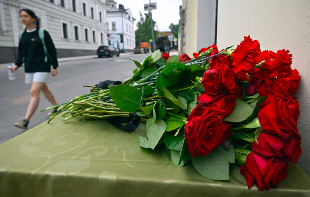 A woman walks past flowers laying in front of the representative office of Dagestan in Moscow on June 24, following terrorist attacks on churches and synagogues.
