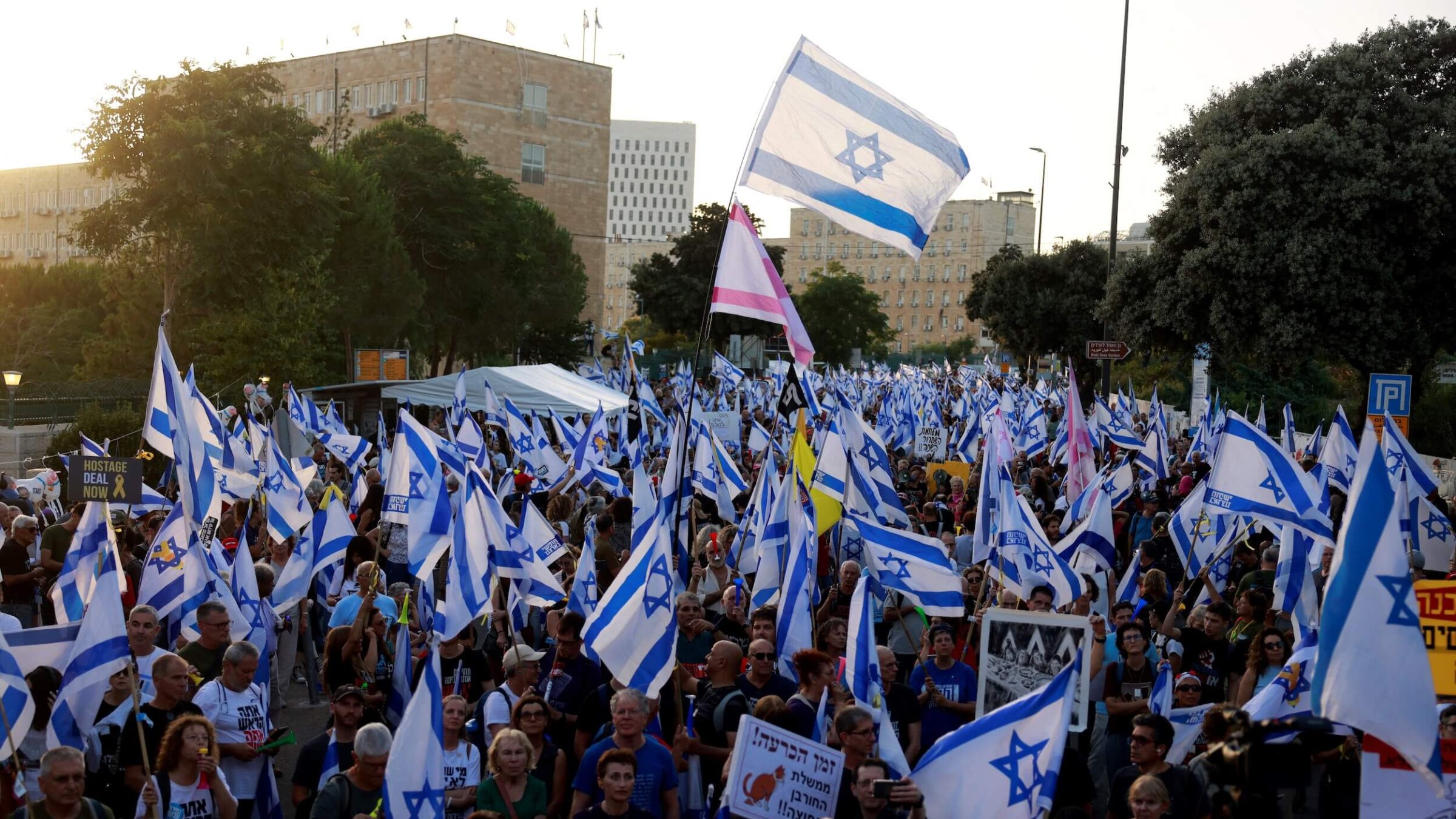 Israelis wave their national flag during an anti-government rally calling for early elections, outside the Knesset on June 18, 2024.