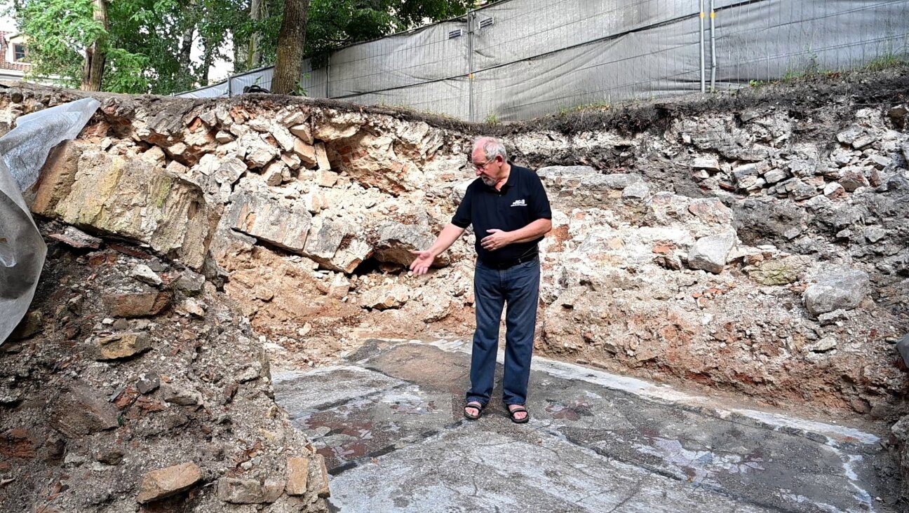 Jon Seligman of the Israel Antiquities Authority stands on the colorful floor of the main prayer hall of the Great Synagogue of Vilna, which was destroyed by the Nazis and has been undergoing excavation since 2015. (Israel Antiquities Authority)