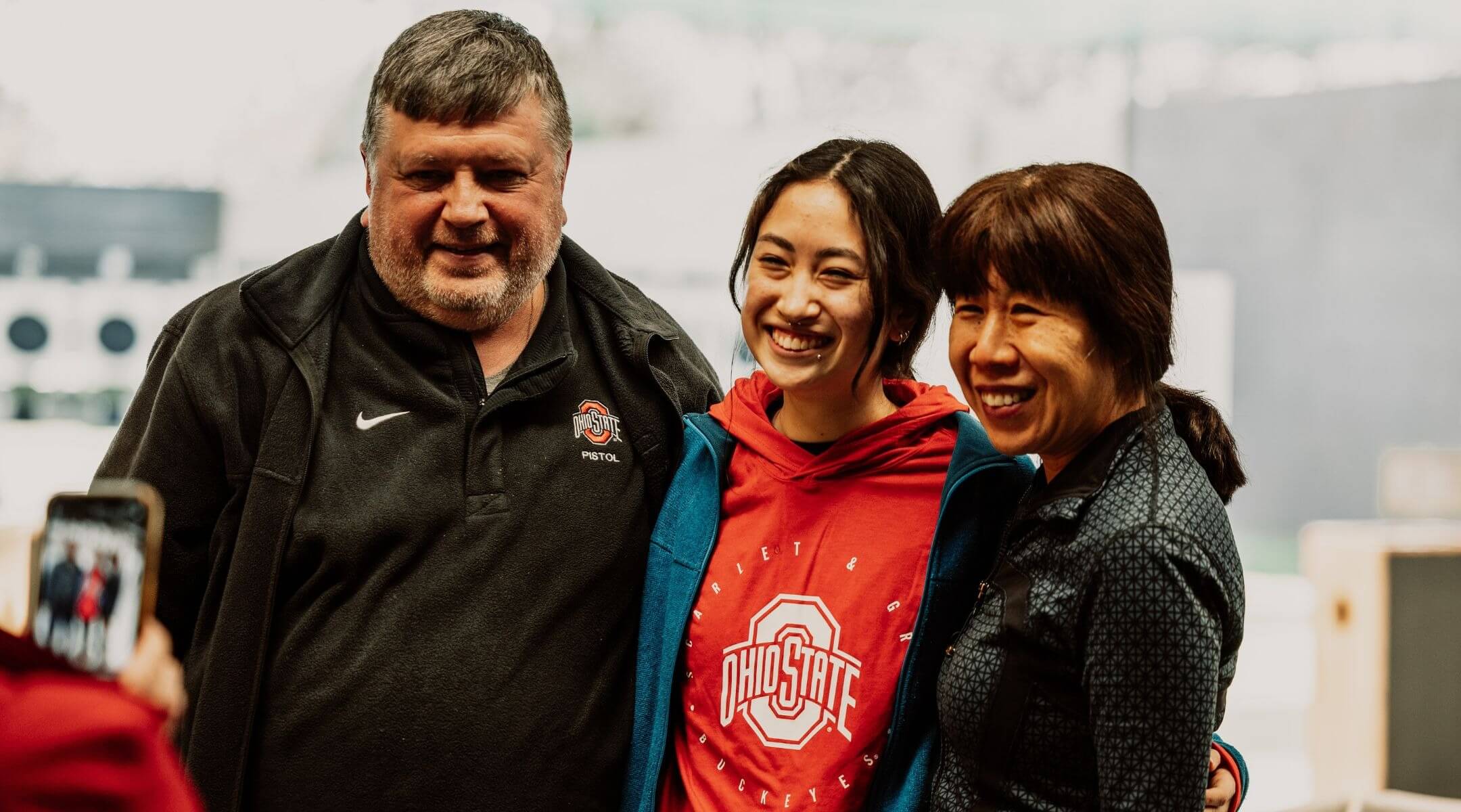 Ada Korkhin, center, celebrates with her parents Yakov Korkhin and May Han at the USA Shooting Olympic qualifiers.