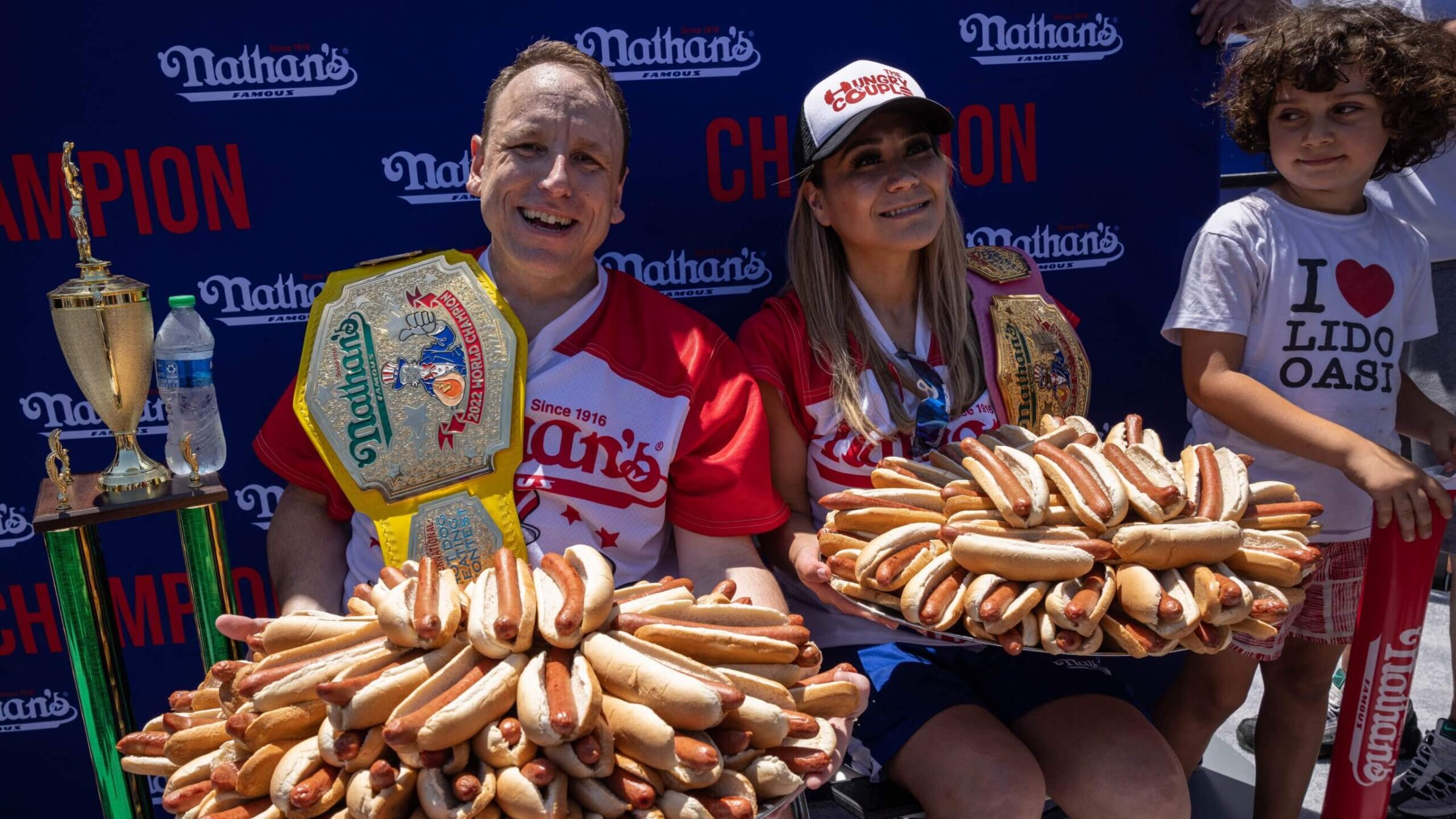 Joey Chestnut, left, and Miki Sudo hold 63 and 40 hot dogs respectively after winning the Nathan's Famous 4th of July 2022 hot dog eating contest on Coney Island. 
