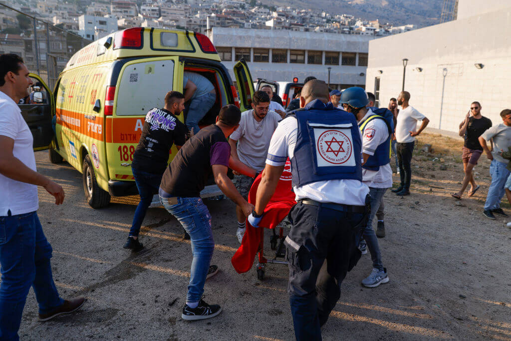 Israeli security forces and medics transport casualties along with local residents, at a site where a reported strike from Lebanon fell in Majdal Shams village in the Israeli-annexed Golan area on July 27.