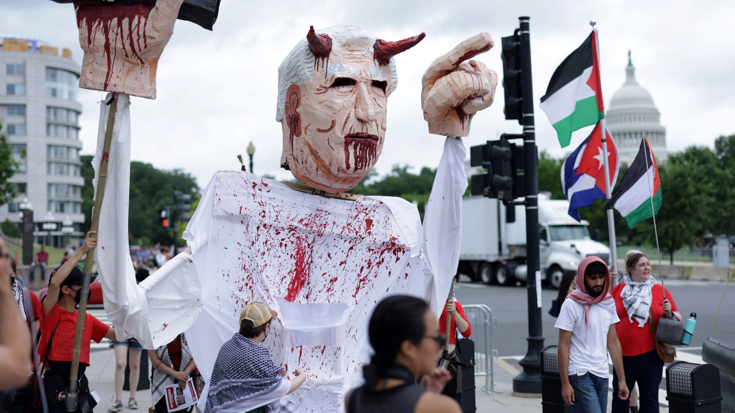 Protesters carry a puppet of a horned Benjamin Netanyahu dripping blood from his mouth.