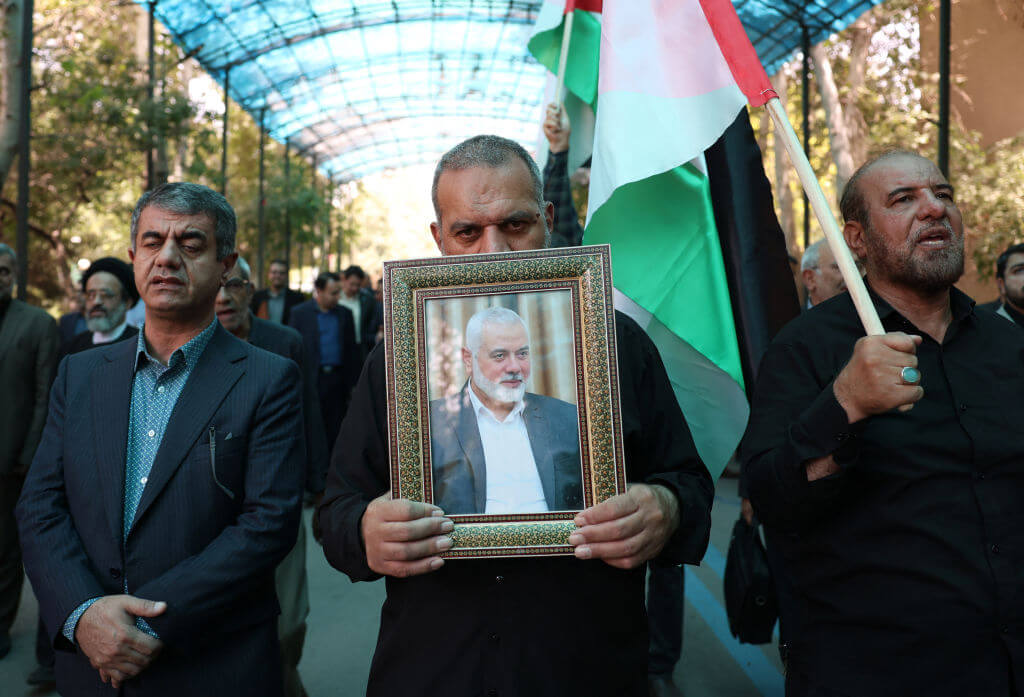 People hold up the Palestinian flag and a portrait of assassinated Hamas chief Ismail Haniyeh Hamas, during a rally at Tehran University July 31.