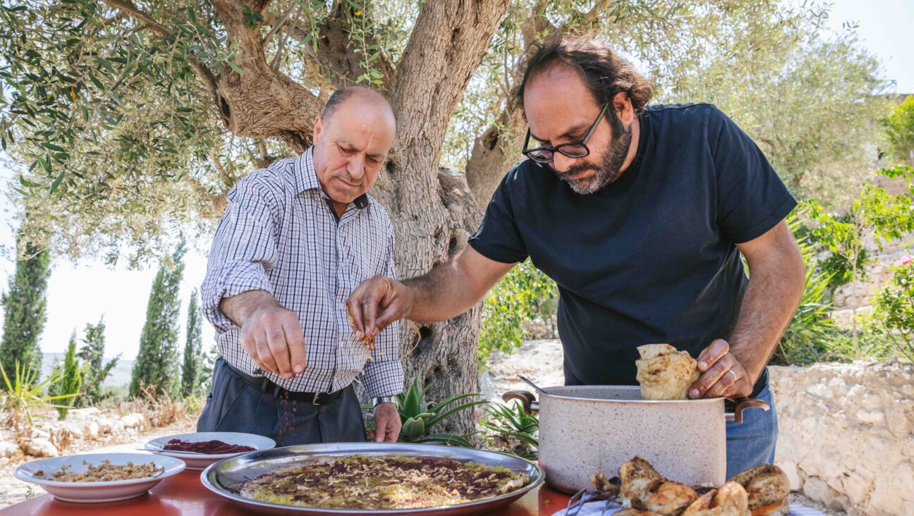Fadi Kattan, right, prepares musakhan, a dish of flatbread and onion confit covered in purple sumac and olive oil, with Abu Mohammad, left, a restaurant owner in the West Bank village of Sebastia. 