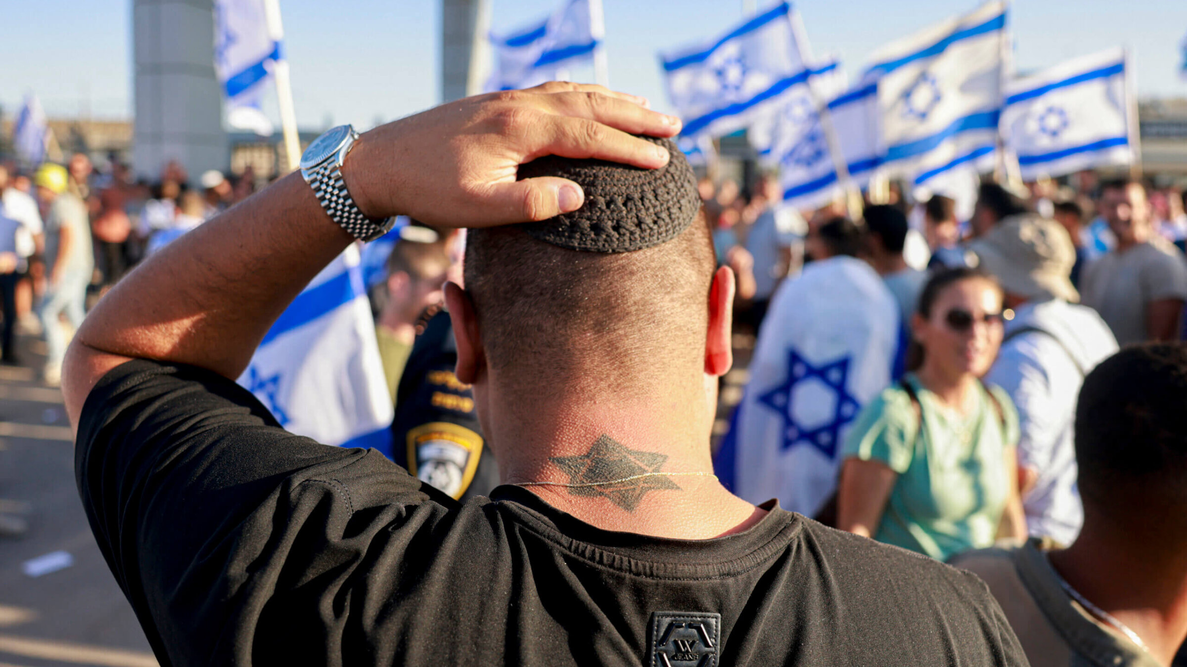 A man adjusts his yarmulke as right-wing Israelis demonstrate at the Sde Teiman military base against the detention for questioning of military reservists suspected of sexually abusing a Palestinian prisoner.