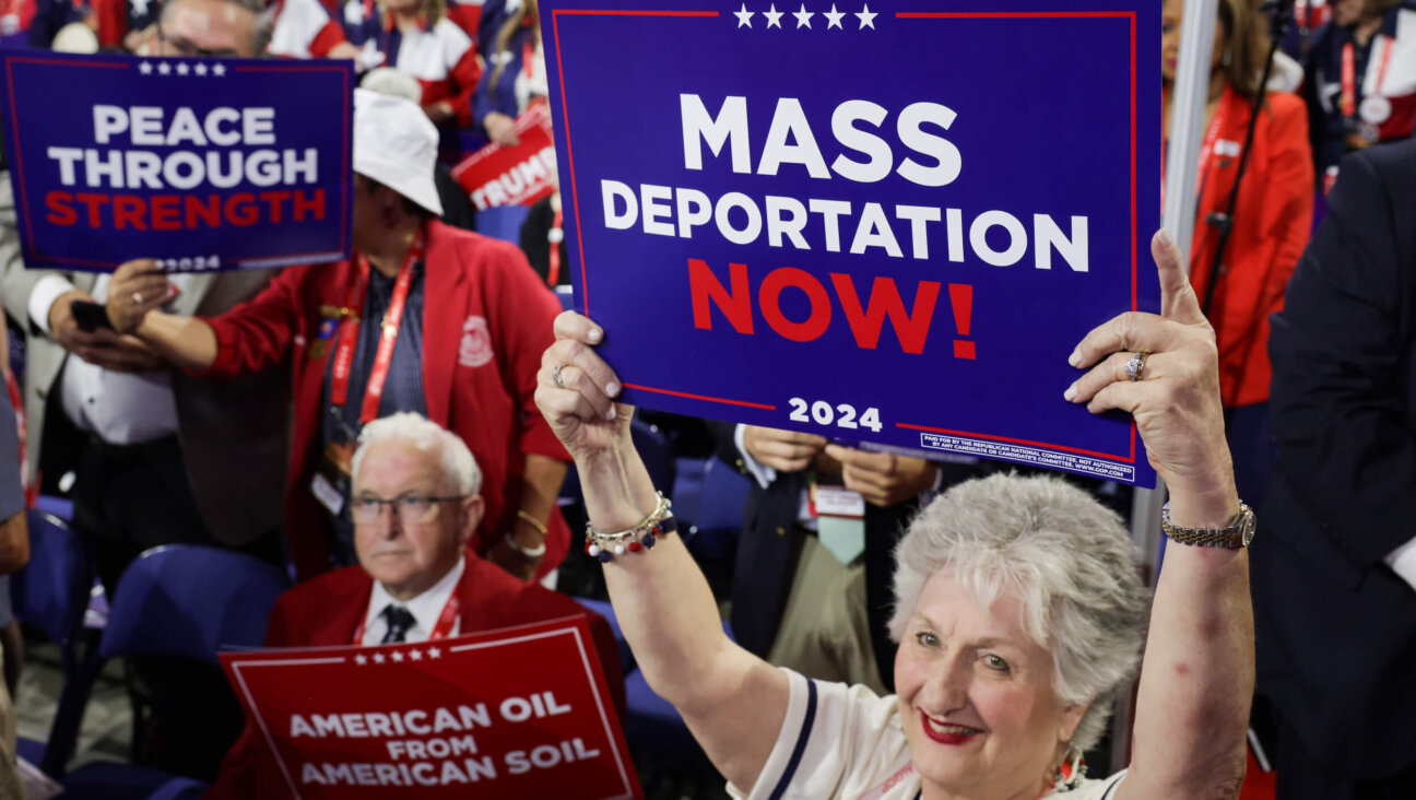 An attendee at the 2024 Republican National Convention holds a sign reading "Mass Deportation Now!" 