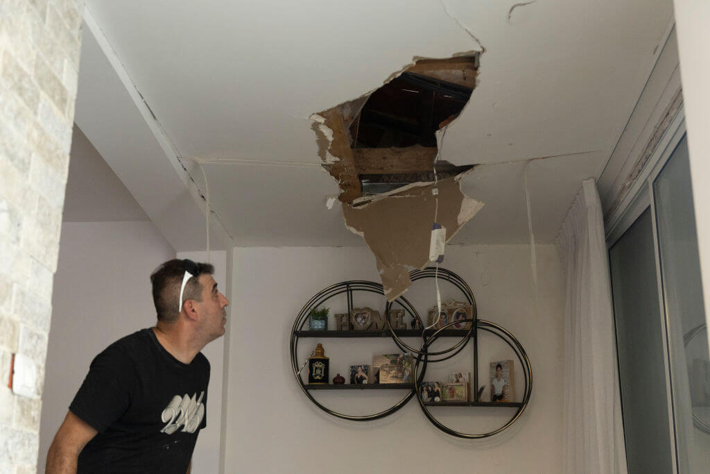 A man inspects the damage of a house after it was hit by a rocket fired from Lebanon on August 25 in Acre, Israel.