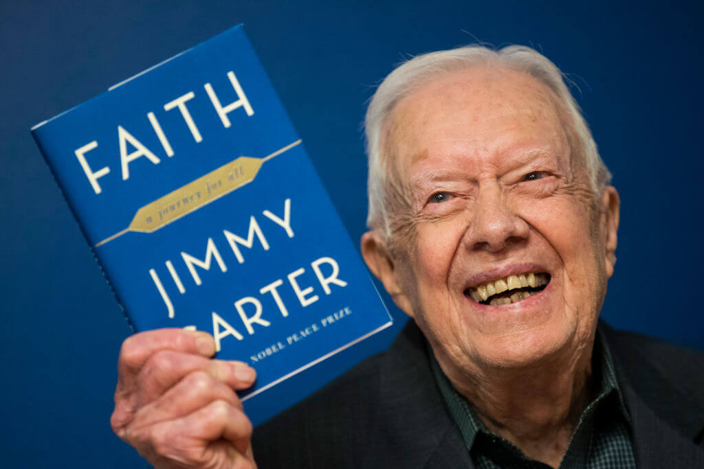 Former President Jimmy Carter holds a copy of his book, "Faith," at an event in 2018.