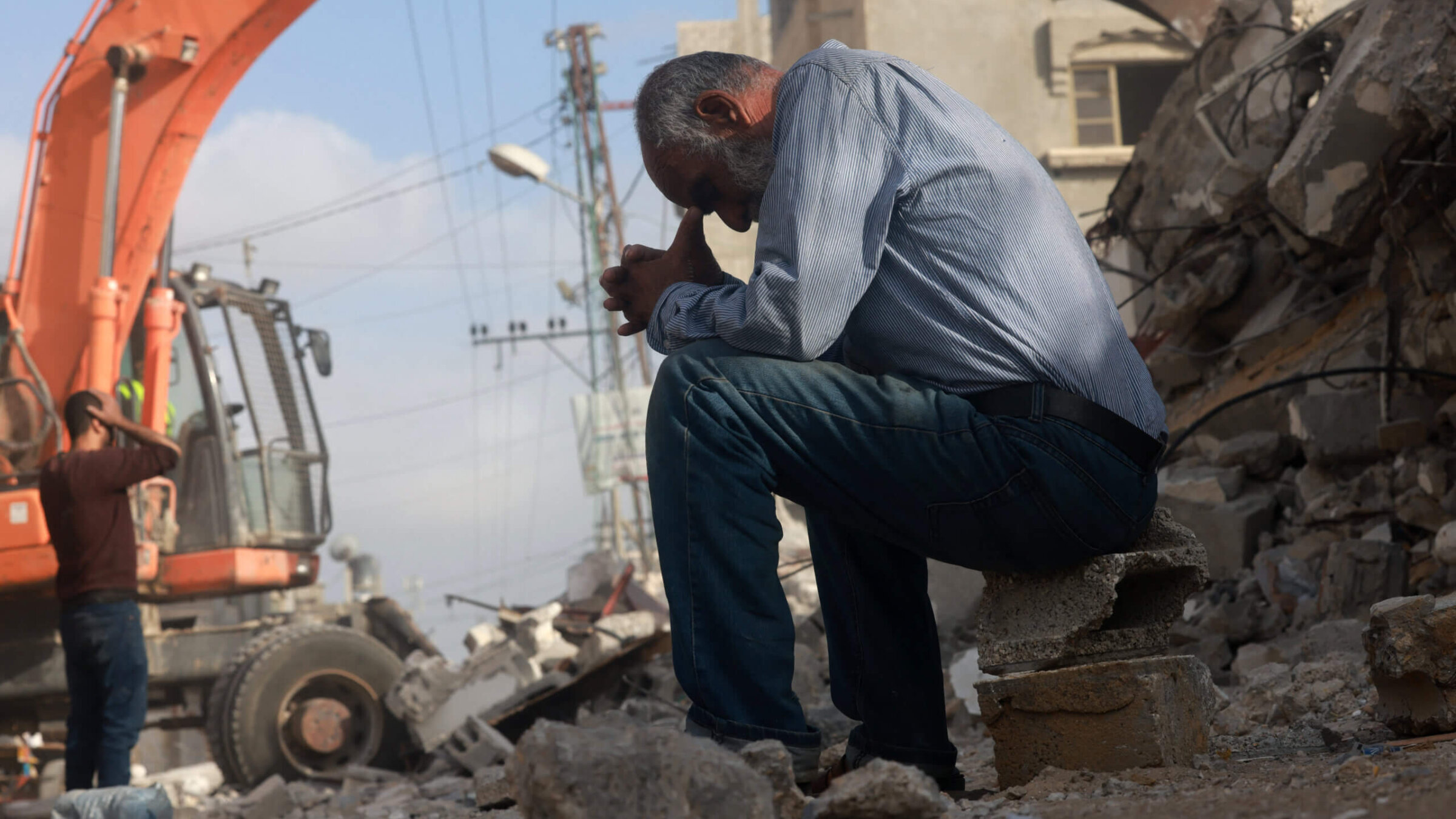 A Palestinian man waits for news of his daughter as rescue workers search for survivors under rubble of a building hit in an overnight Israeli bombing in Rafah, April 21, 2024.