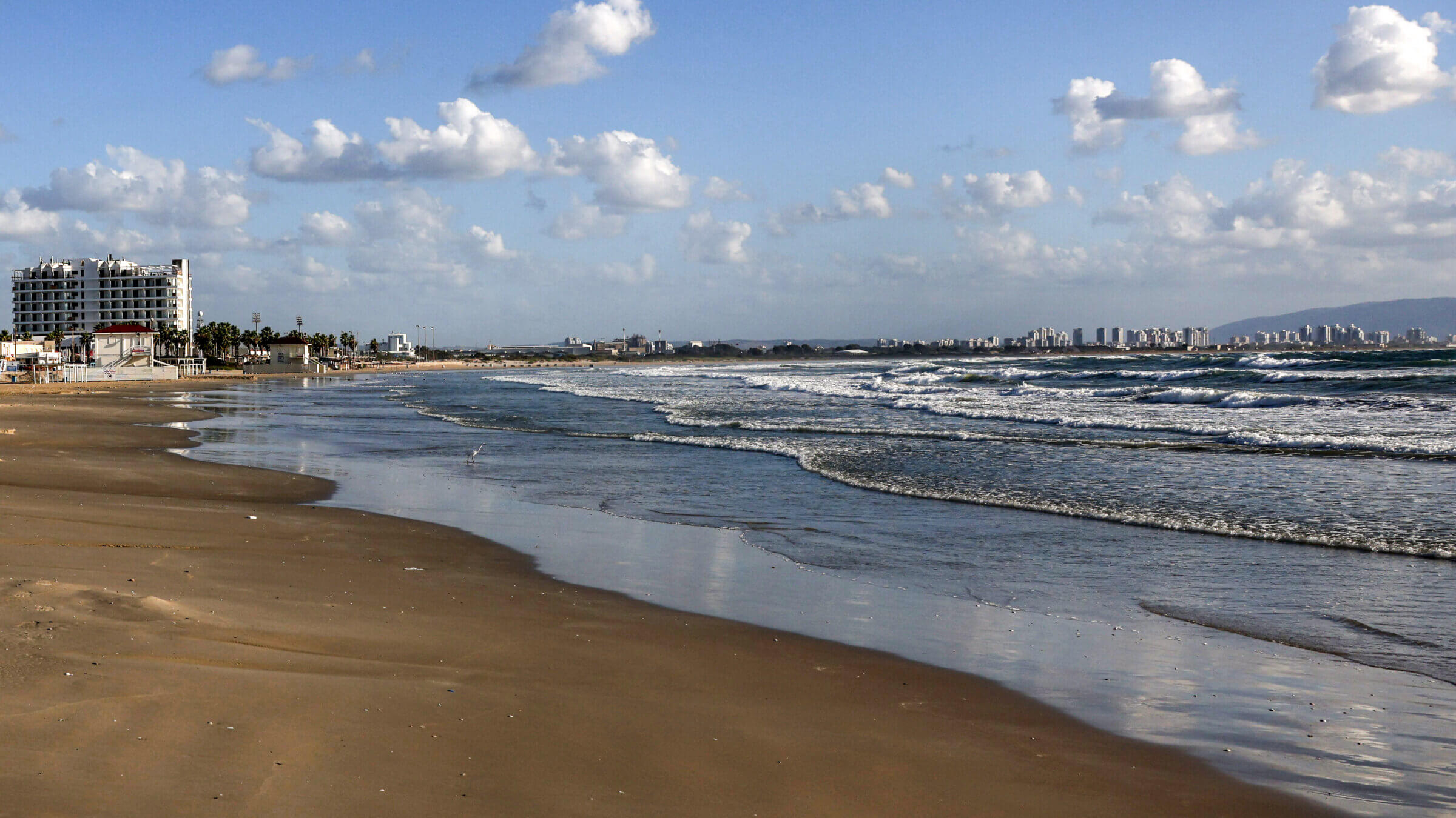 An empty beach overlooking the Mediterranean sea in Acre, just across from the Haifa skyline on the right. 