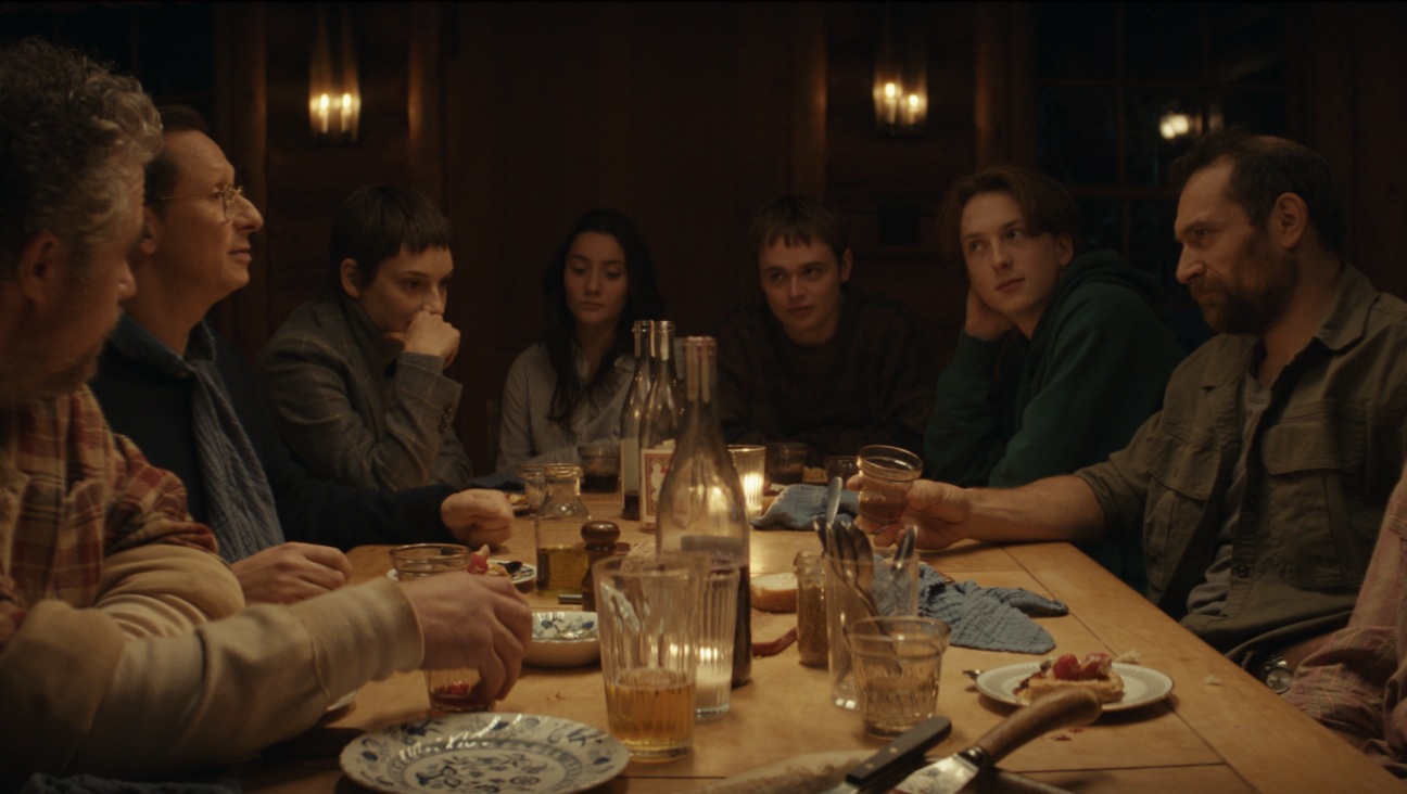 Guests at a remote cabin share a meal in Philippe Lesage's <i>Who by Fire.</i>
