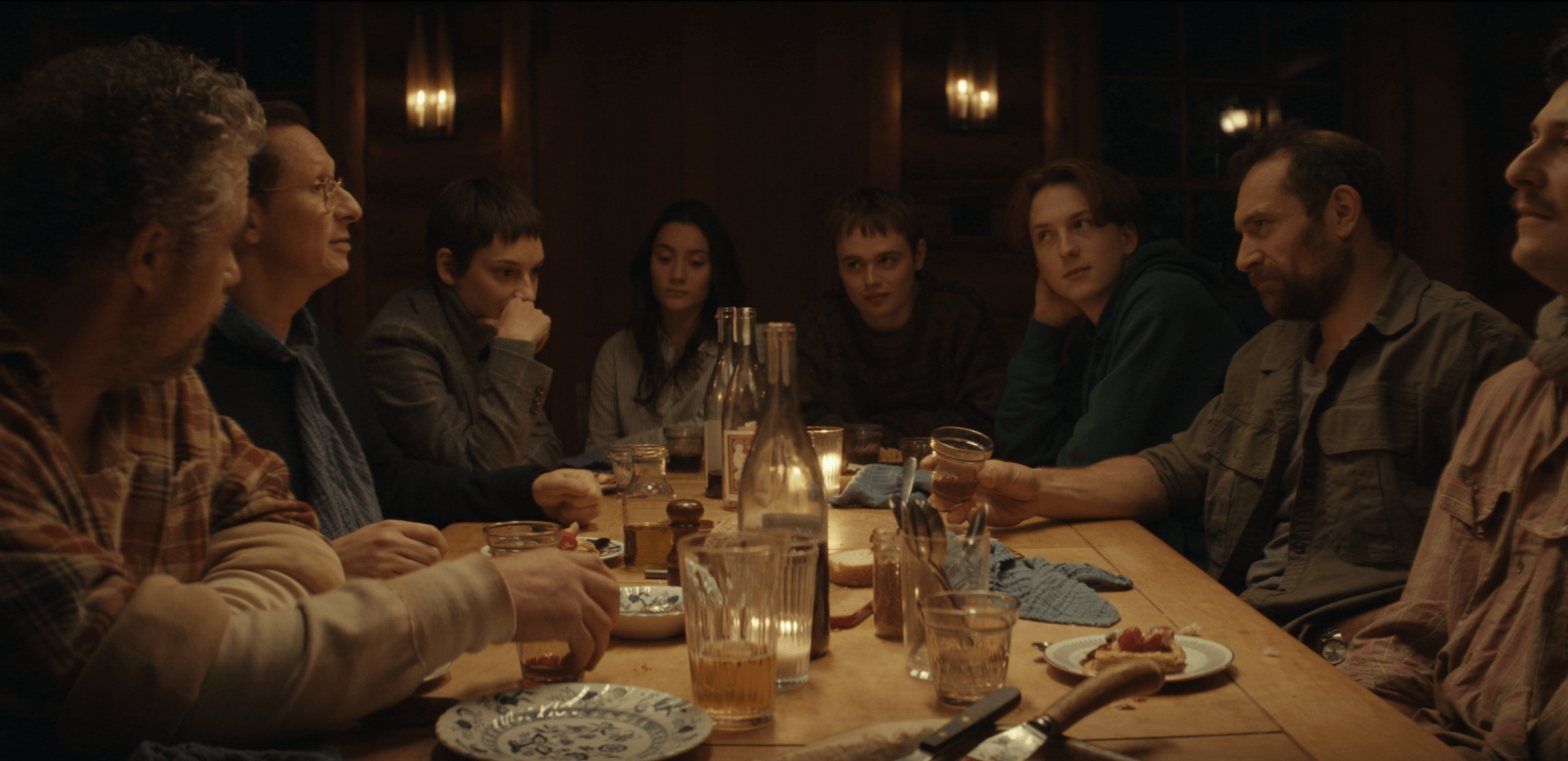 Guests at a remote cabin share a meal in Philippe Lesage's <i>Who by Fire.</i>
