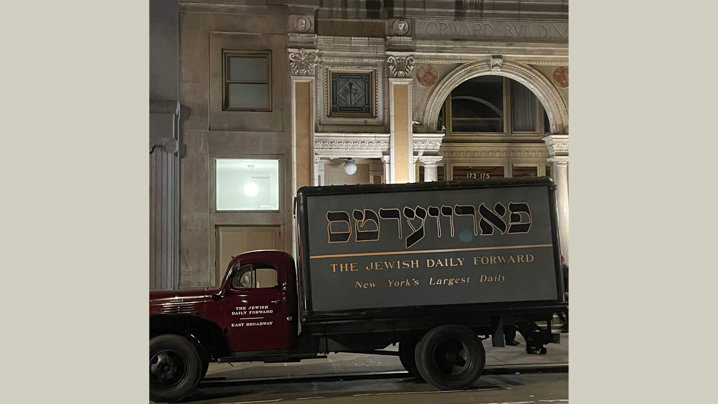 A truck with <i>Forverts</i> written on the side in Hebrew lettering in front of the Forward Building on East Broadway.