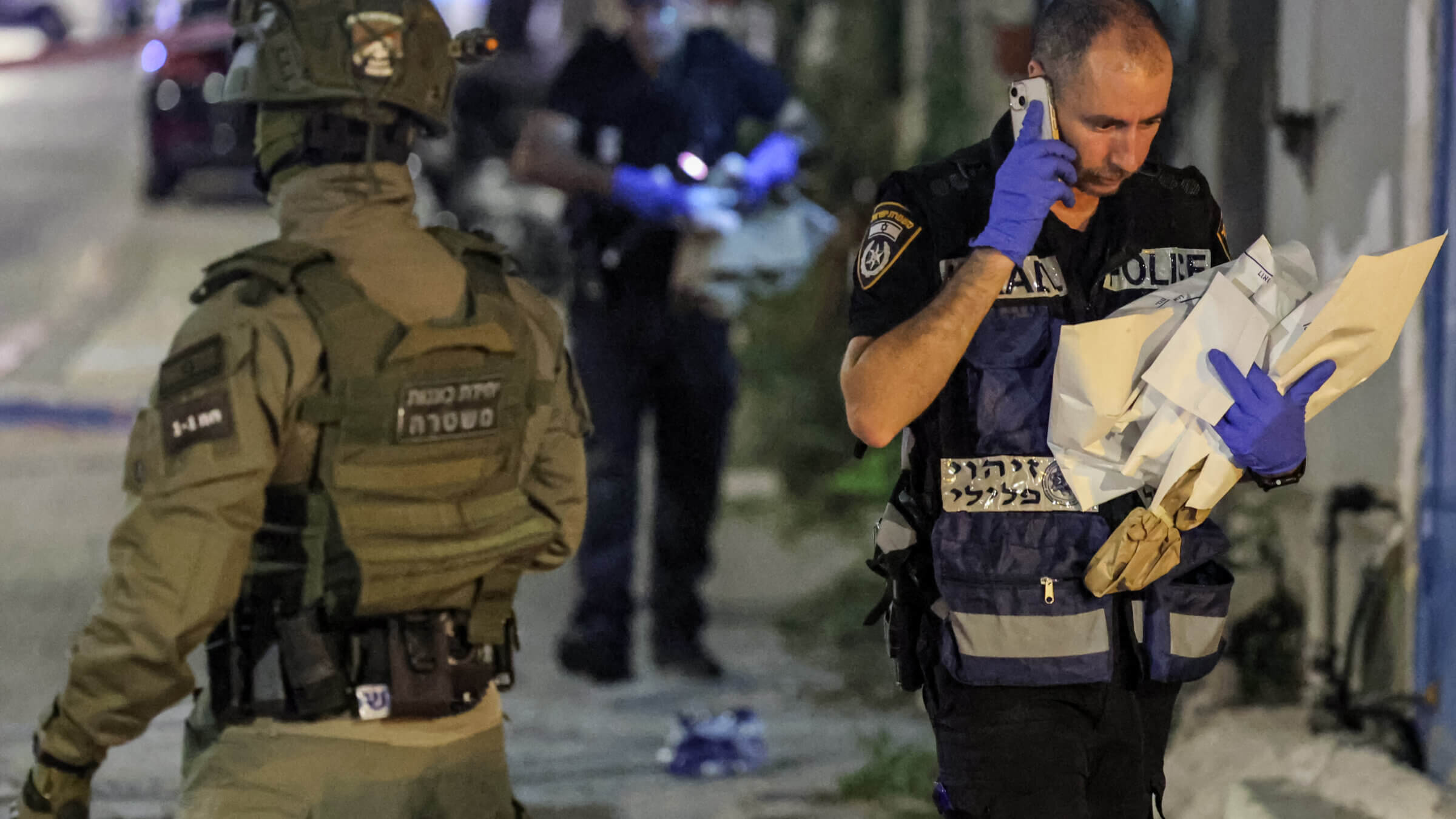 A member of the Israeli police's forensics department walks past a special forces member at the scene of a shooting attack in Jaffa south of Tel Aviv on October 1, 2024. At least four people were shot dead on October 1 in a suspected attack in Israel's central city of Tel Aviv, police said, adding that the two assailants had been "neutralised". 