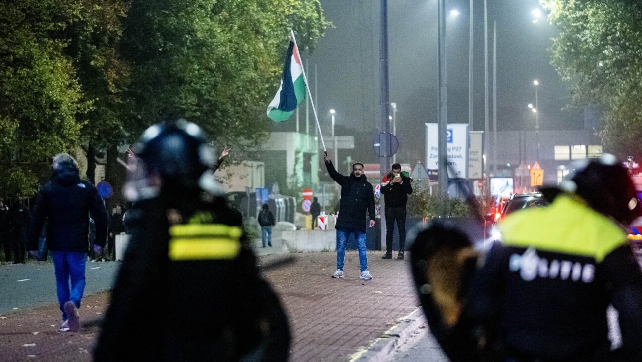 A man waves a Palestinian flag in front of police officers during a pro-Palestinian demonstration on the sideline of the UEFA Europa League football match between AFC Ajax and Maccabi Tel Aviv in Amsterdam on Nov. 7.