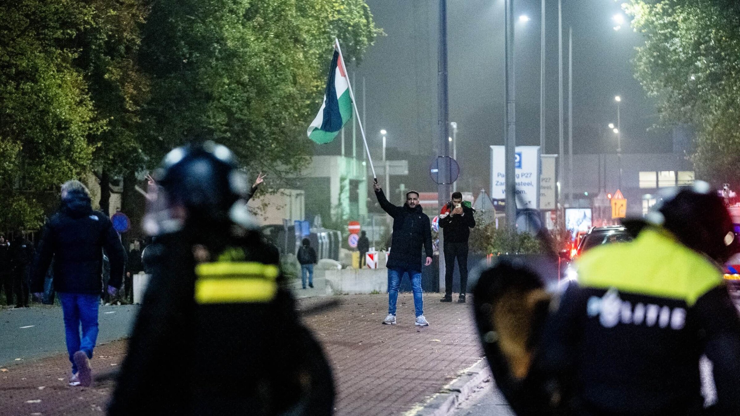 A man waves a Palestinian flag in front of police officers during a pro-Palestinian demonstration on the sideline of the UEFA Europa League football match between AFC Ajax and Maccabi Tel Aviv in Amsterdam on Nov. 7.