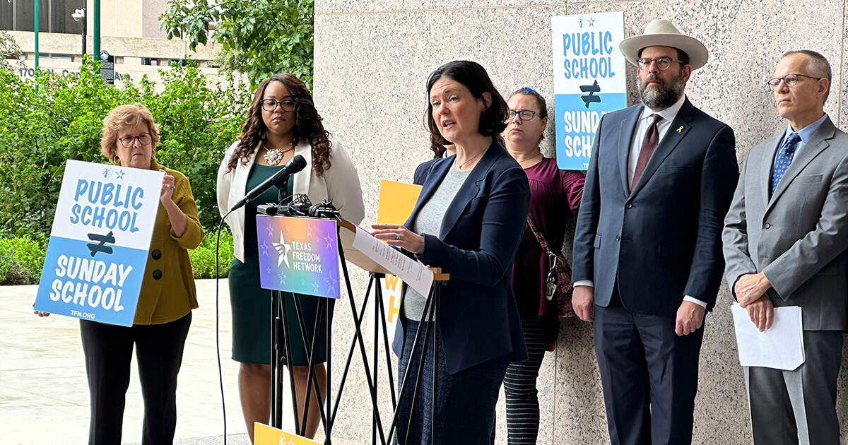 
Amanda Tyler of the Baptist Joint Committee for Religious Liberty speaks at a press conference outside a hearing of the Texas State Board of Education on adopting a Bible-infused curriculum for public schools. Rabbi Neil Blumofe is in the back, wearing a hat.