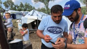 HIAS Greece translator Jalal Barezkai, right, assists a Syrian refugee in an encampment near the Moria refugee camp on the island of Lesbos, Greece, May 9, 2018. (Bill Swersey/HIAS)