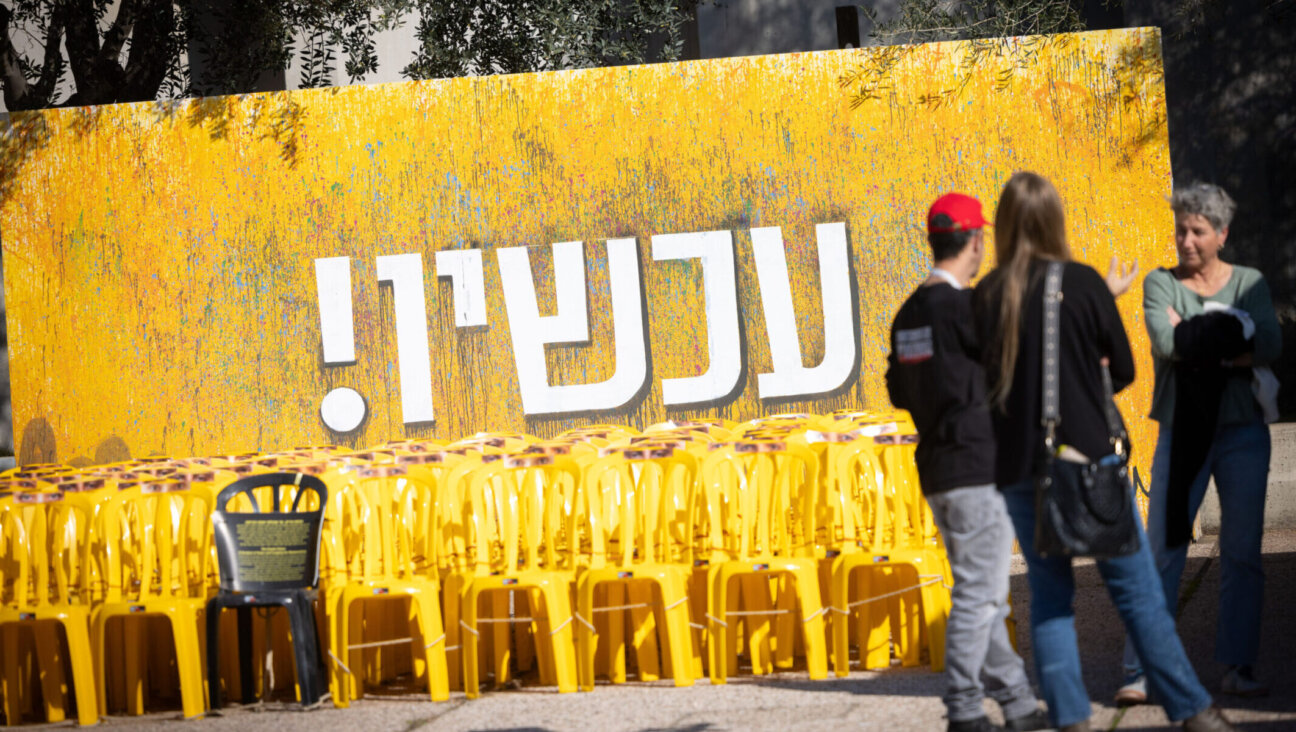 Visitors at Hostage Square in Tel Aviv stand in front of a sign reading “Now!” in Hebrew, Jan. 6, 2025. (Miriam Alster/Flash90)