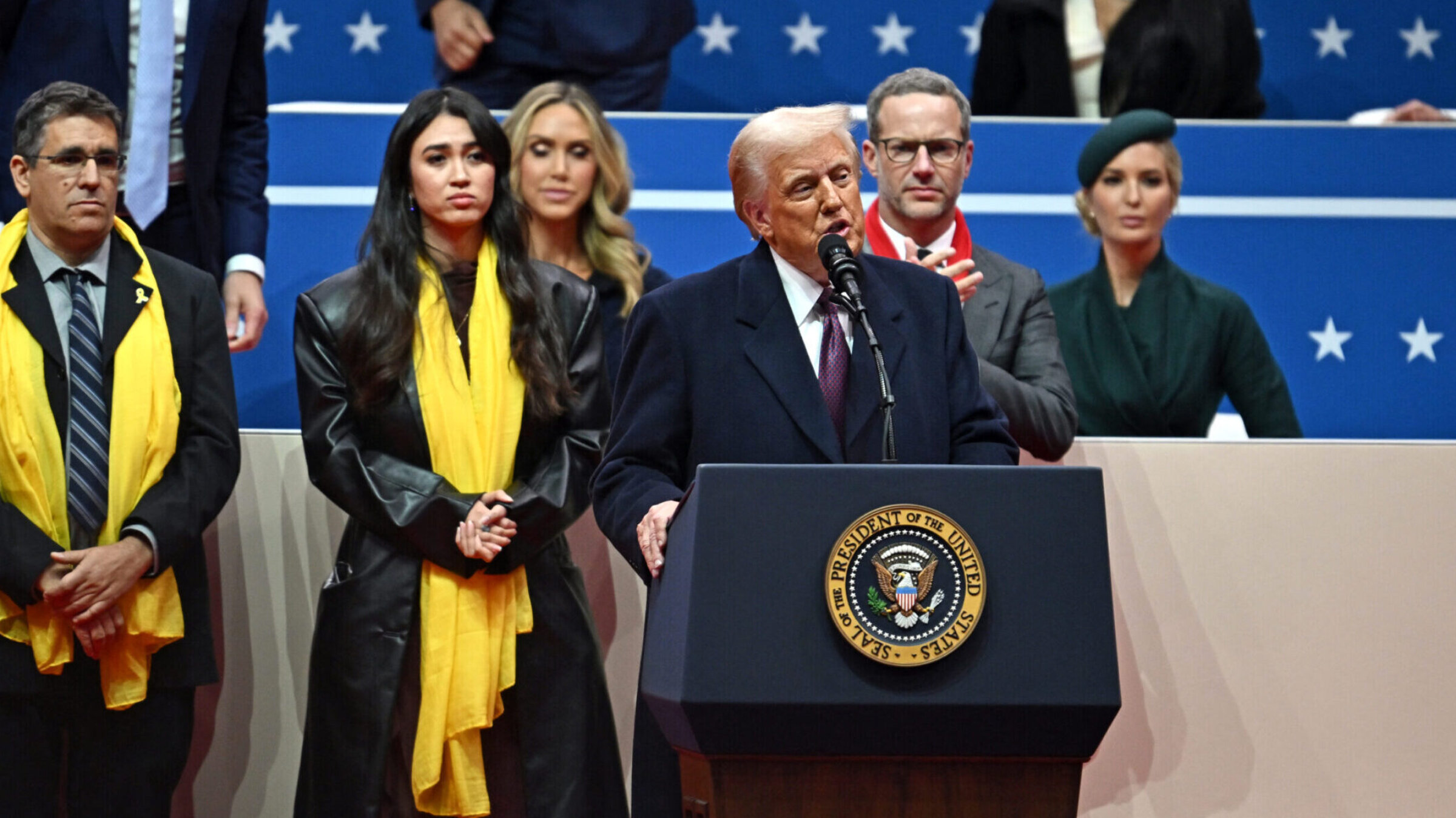 President Donald Trump speaks during the inaugural parade on Jan. 20, 2025, with Noa Argamani, an Israeli former hostage, standing behind him. 