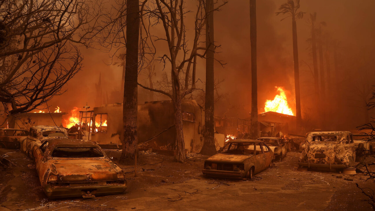 Burned cars sat parked in front of a burning home as the Eaton Fire moved through Altadena, California, on Wednesday.