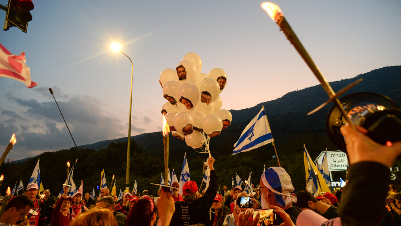 A demonstrator holds white balloons with the faces of Israeli Prime Minister Benjamin Netanyahu and his governing cabinet on them, while others carry torches and Israeli flags at a protest calling for an end to Israel's war in the Gaza Strip Jan. 11, 2025, in Kiryat Shmona, Israel.