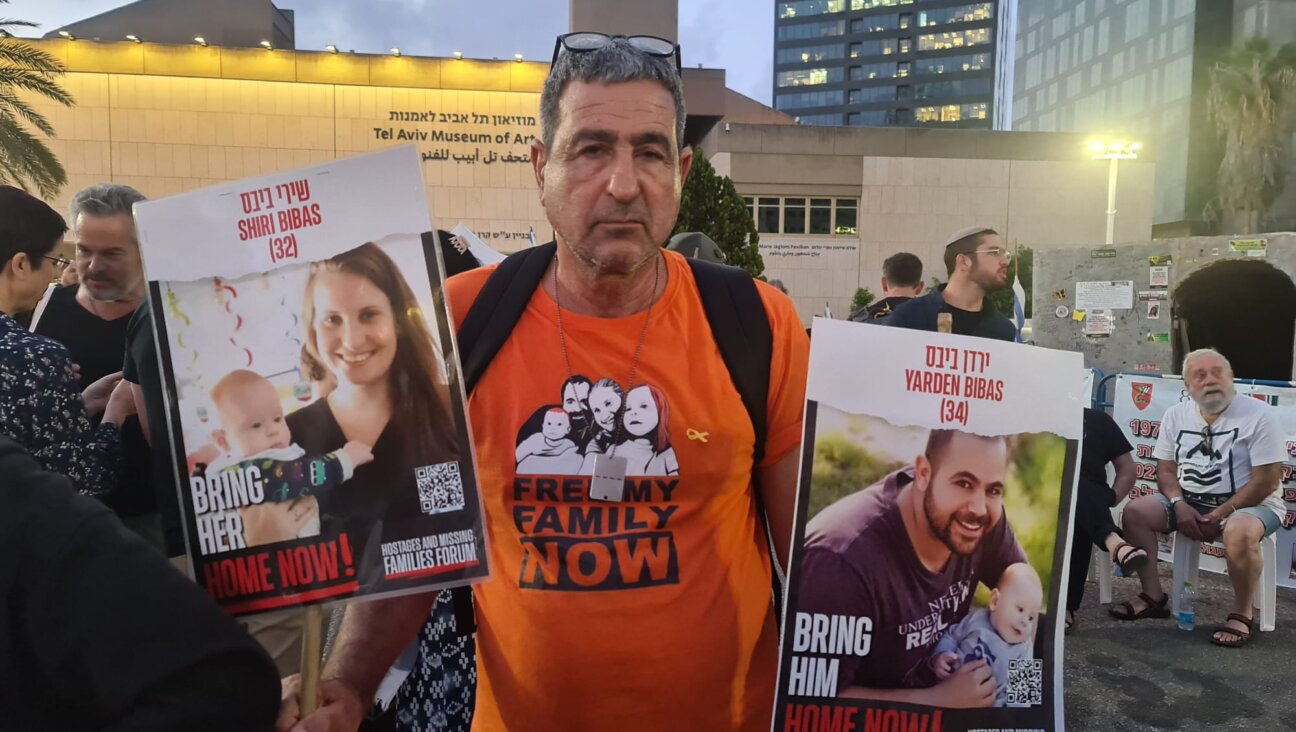 Eli Bibas holds pictures of his grandsons, who remain hostages in Gaza, during a pre-Passover rally in Tel Aviv. (Deborah Danan)