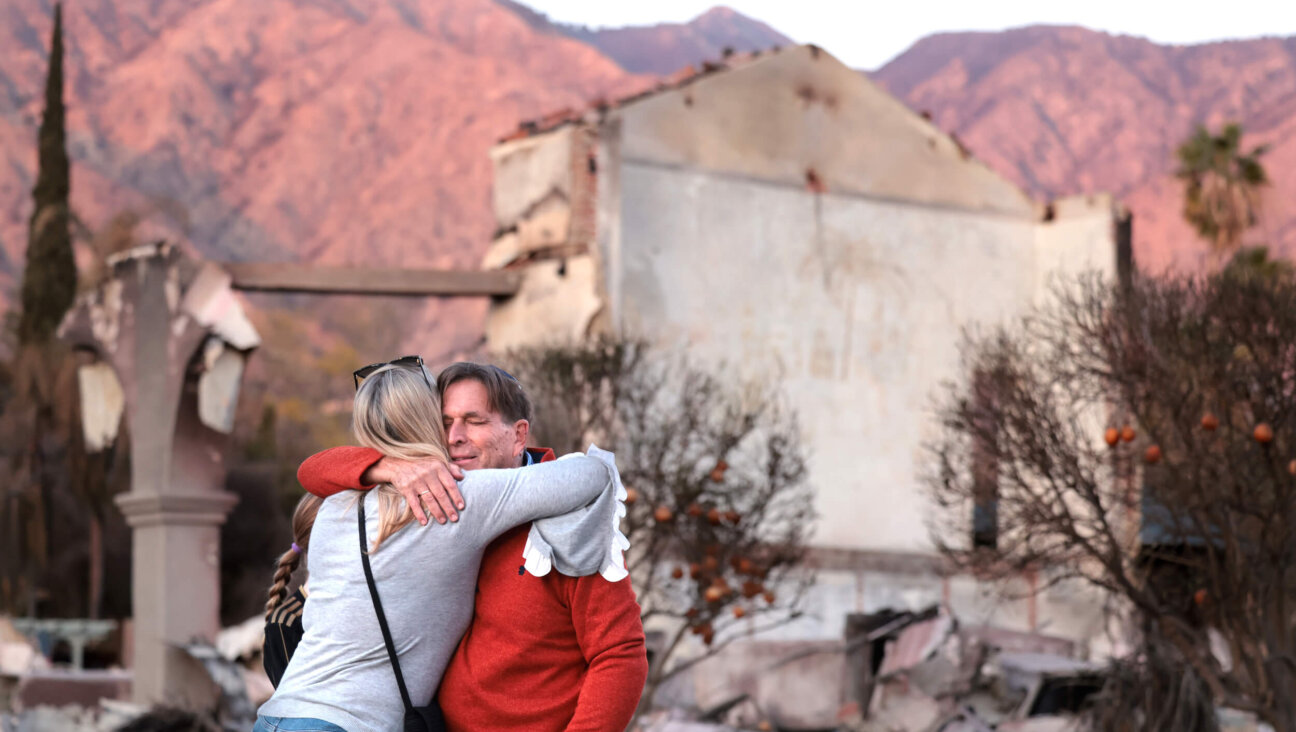 Congregants hug in front of what's left of the Pasadena Jewish Temple and Center after it was destroyed by the Eaton Fire.