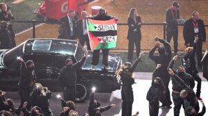 A protester holds a Sudan/Palestinian flag with the words “Gaza” and “Sudan” as US rapper Kendrick Lamar performs during thee Super Bowl LIX halftime show, Feb. 9, 2025. (Chandan Khanna/AFP via Getty Images)