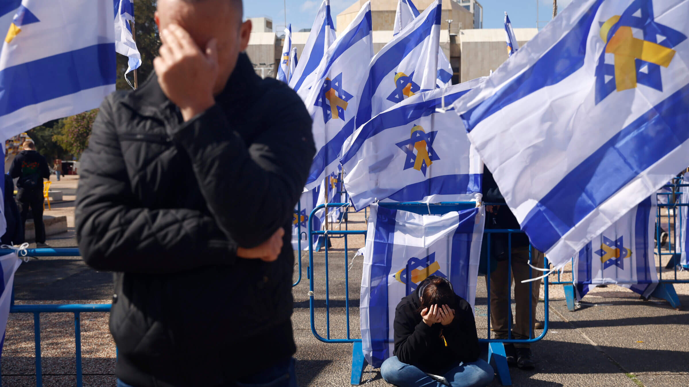 People react among Israeli flags in Hostage Square prior to the handover of four bodies taken by Hamas.