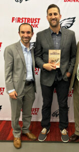 Rabbi Zev Eleff, left, with Nick Sirianni, the coach of the Philadelphia Eagles, who is holding a copy of Eleff's book about faith and football.