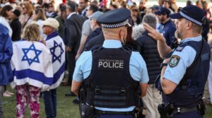 New South Wales police officers stand near members of the Australian Jewish community holding a memorial service for six Israeli hostages whose bodies were recovered from the Gaza Strip, at Sydney’s Bondi Beach on Sept. 2, 2024. (David Gray / AFP via Getty Images)