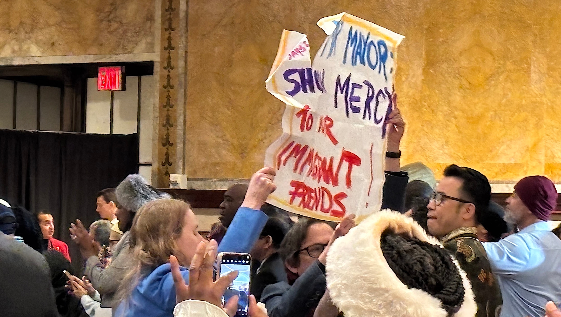 Rabbi Sharon Kleinbaum (center, in glasses) and Rabbi Jill Jacobs of T’ruah (left) hold a sign reading “Mr. Mayor, show mercy to our immigrant friends,” at New York Mayor Eric Adams’s annual interfaith breakfast, held Jan. 30, 2025 at the New York Public Library. (Courtesy The Beacon)