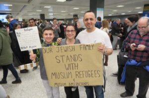 Jacob, left, Miri and Tal Zlotnitsky hold up a poster welcoming Muslim arrivals at Dulles International Airport in Virginia, Jan. 28, 2017. (Ron Kampeas)