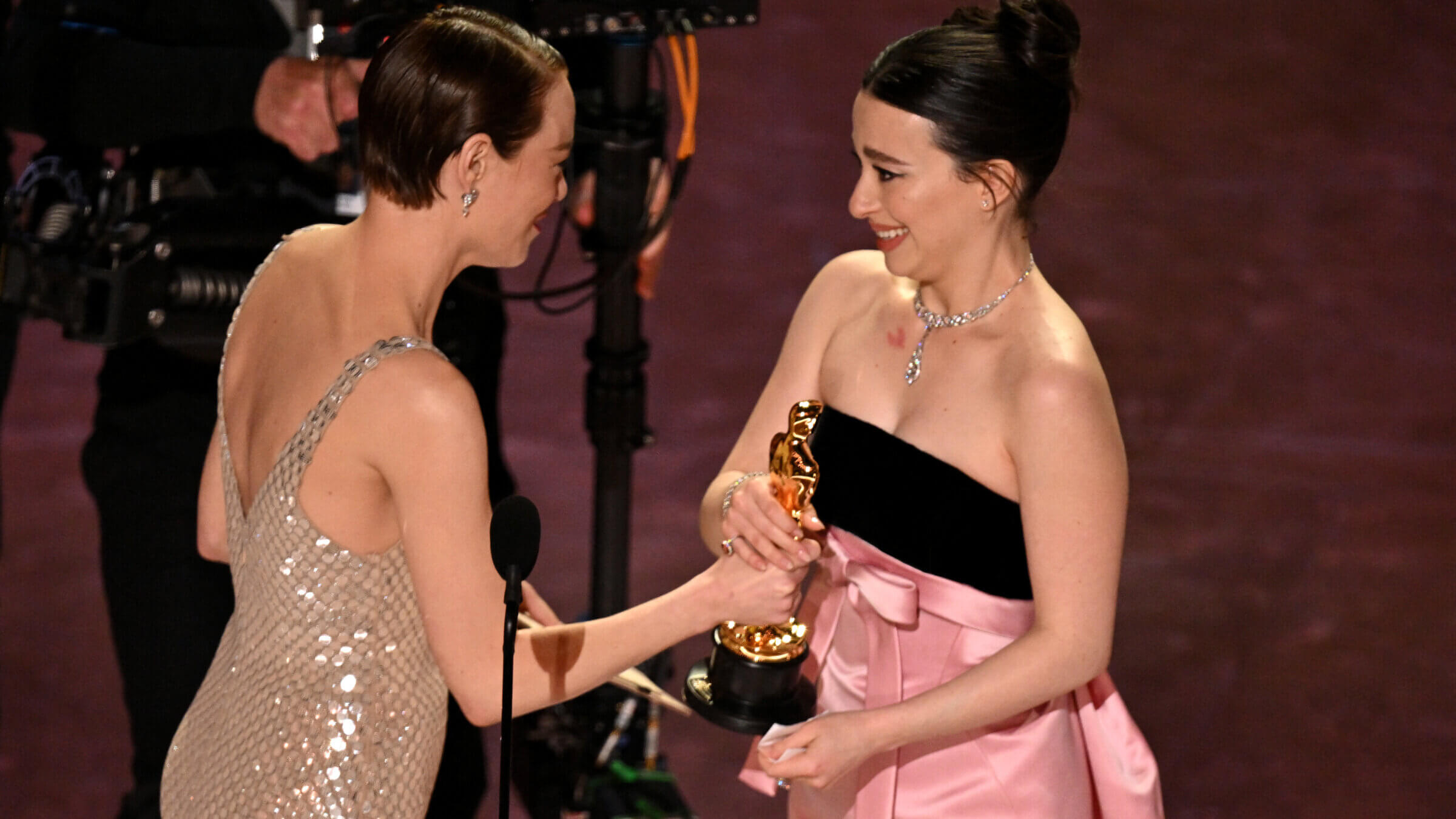 Mikey Madison, who played a sex worker in <i>Anora</i>, accepts the best actress award from Emma Stone, who played a sex worker in <i>Poor Things</i>.