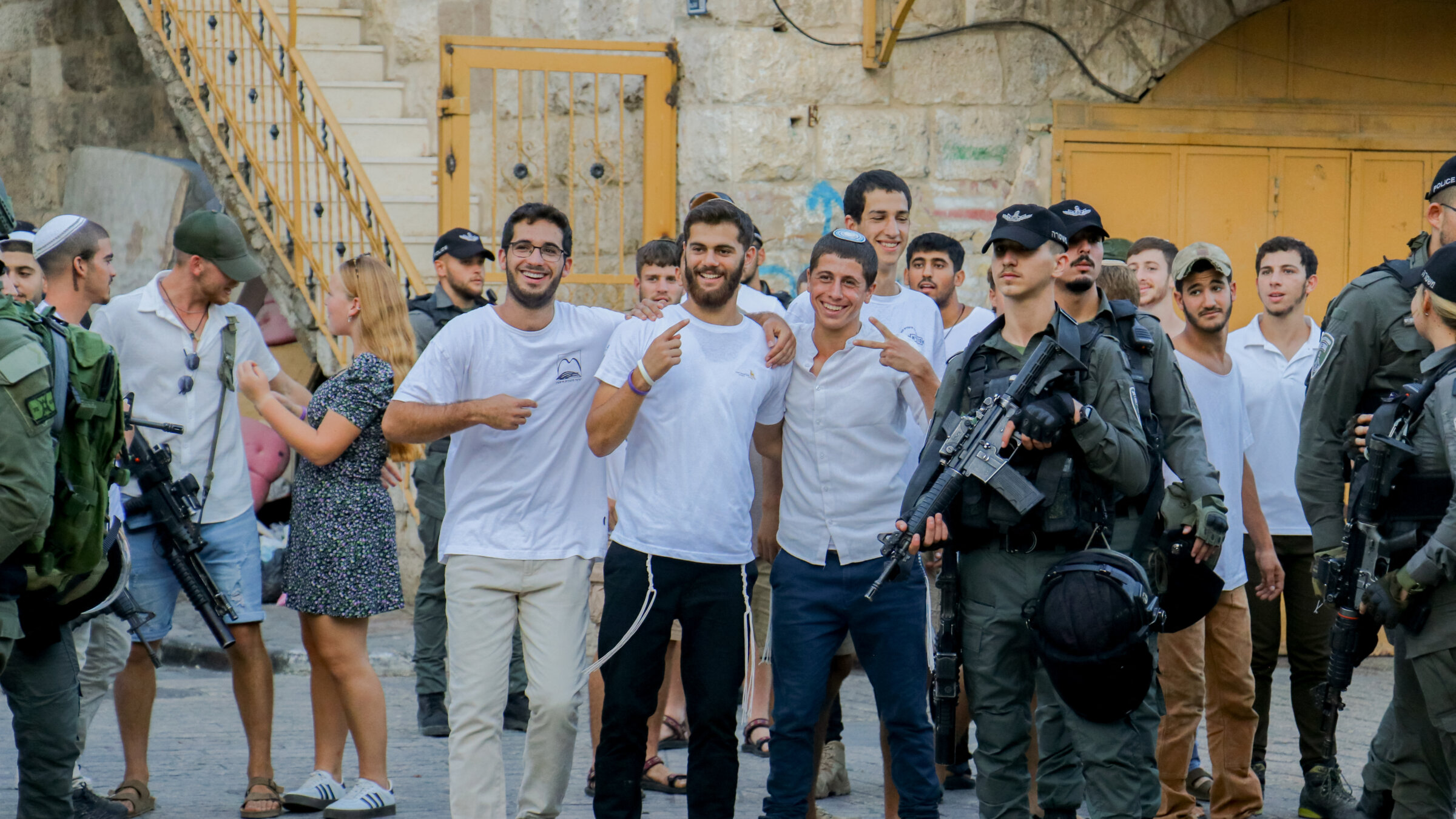 Settlers in the West Bank pose for a photo as Israeli soldiers stand nearby during a march in Hebron, Sept. 28, 2024. 
