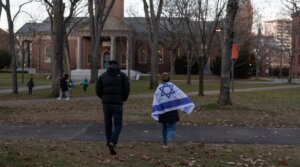 A person draped in an Israeli flag attends a menorah lighting ceremony at Harvard University on Dec. 13, 2023, Cambridge, Massachusetts. (Andrew Lichtenstein/Corbis via Getty Images)