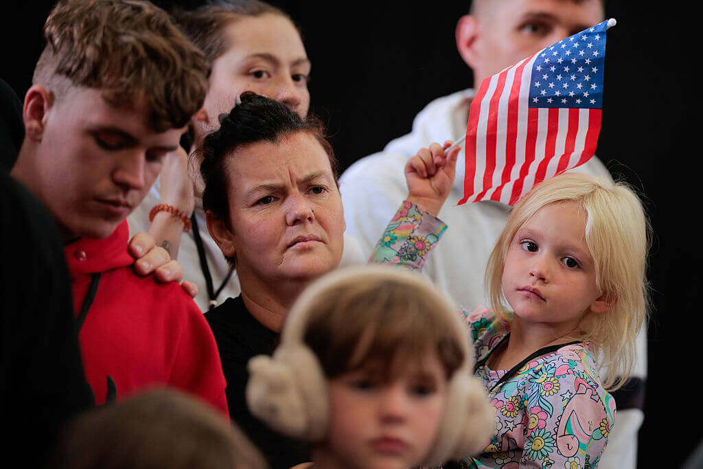 Newly arrived South Africans listen to officials from Homeland Security and the State Department deliver welcome remarks in a hangar near Washington Dulles International Airport in May 2025.