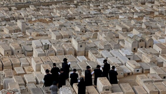 A group of Orthodox Jews pray over tombs at the cemetery on the Mount of Olives in Jerusalem in January 2023.
