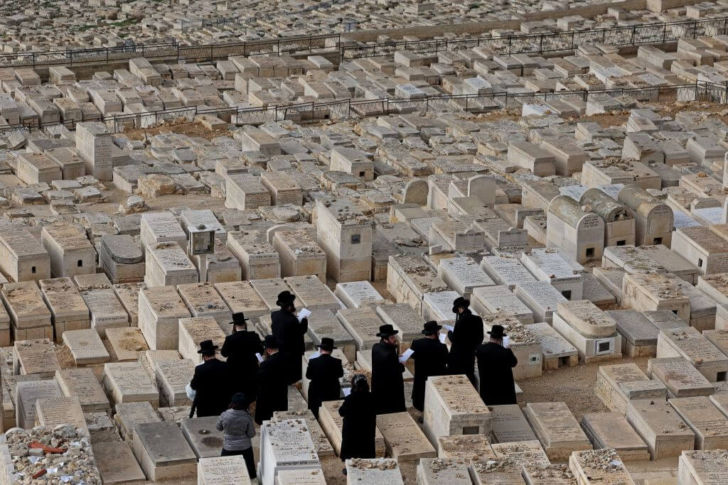 A group of Orthodox Jews pray over tombs at the cemetery on the Mount of Olives in Jerusalem in January 2023.
