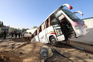 People check a bus inside a crater on May 14, 2025, in the aftermath of an Israeli strike in Khan Yunis in the southern Gaza Strip. (Getty)