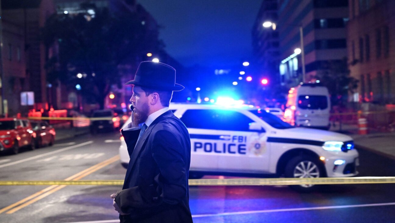 A man, standing behind police tape, talks on his cell phone outside the Capital Jewish Museum following a shooting that left two people dead, in Washington, DC, in the early hours of May 22, 2025. Two Israeli embassy staffers were killed in the shooting. (Alex Wroblewski/AFP via Getty Images)