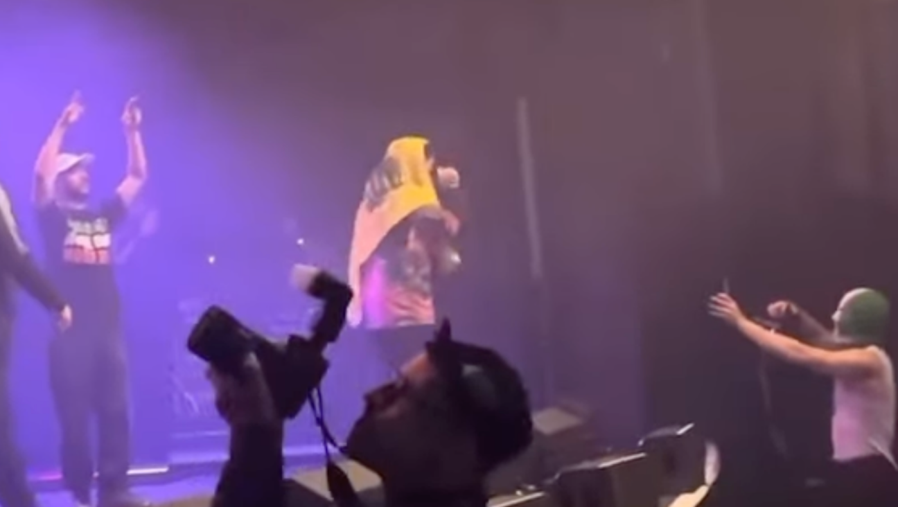 Kneecap band member Liam O’Hanna displaying the Hezbollah flag at a November 2024 concert. (Screenshot)